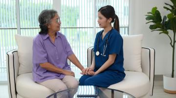 A female doctor is checking the temperature of an elderly patient.